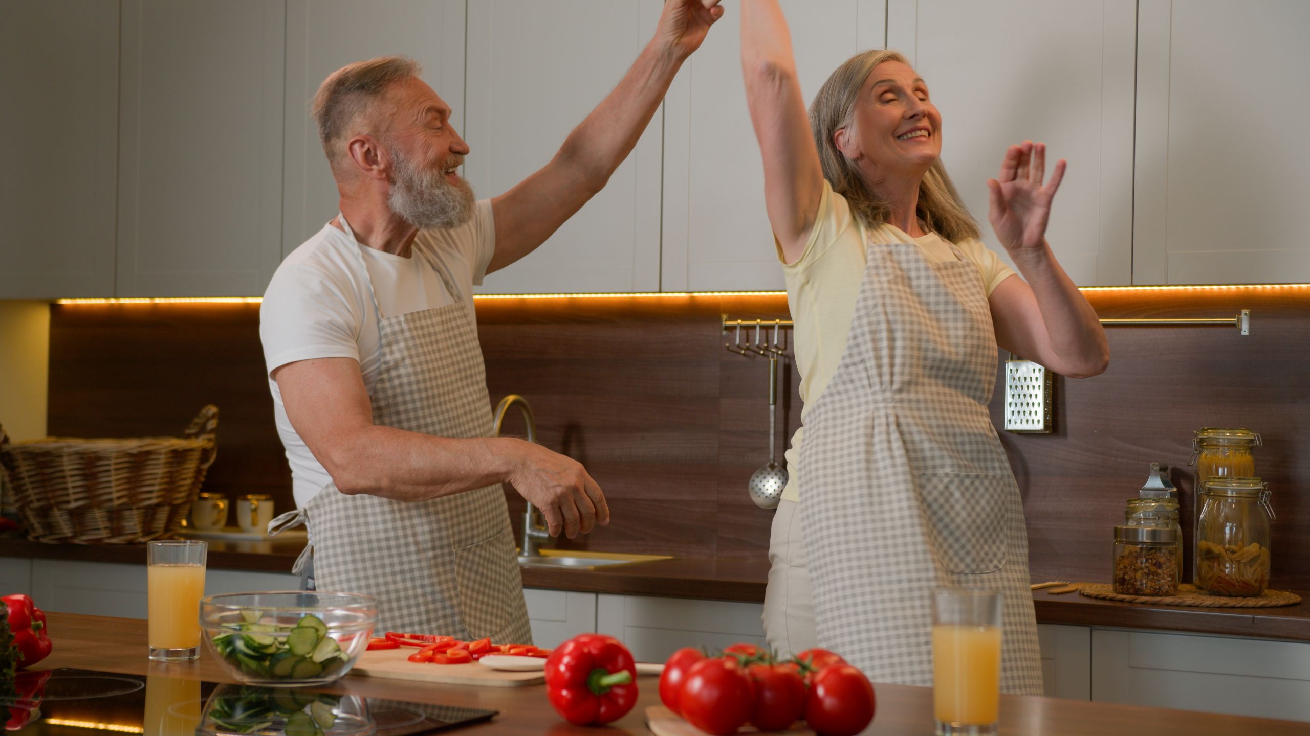 Romantic senior retired Caucasian family couple dancing waltz celebrate marriage anniversary cooking dinner old husband spin mid-aged wife in dance listen music at kitchen happy woman and man have fun. High quality 4k footage